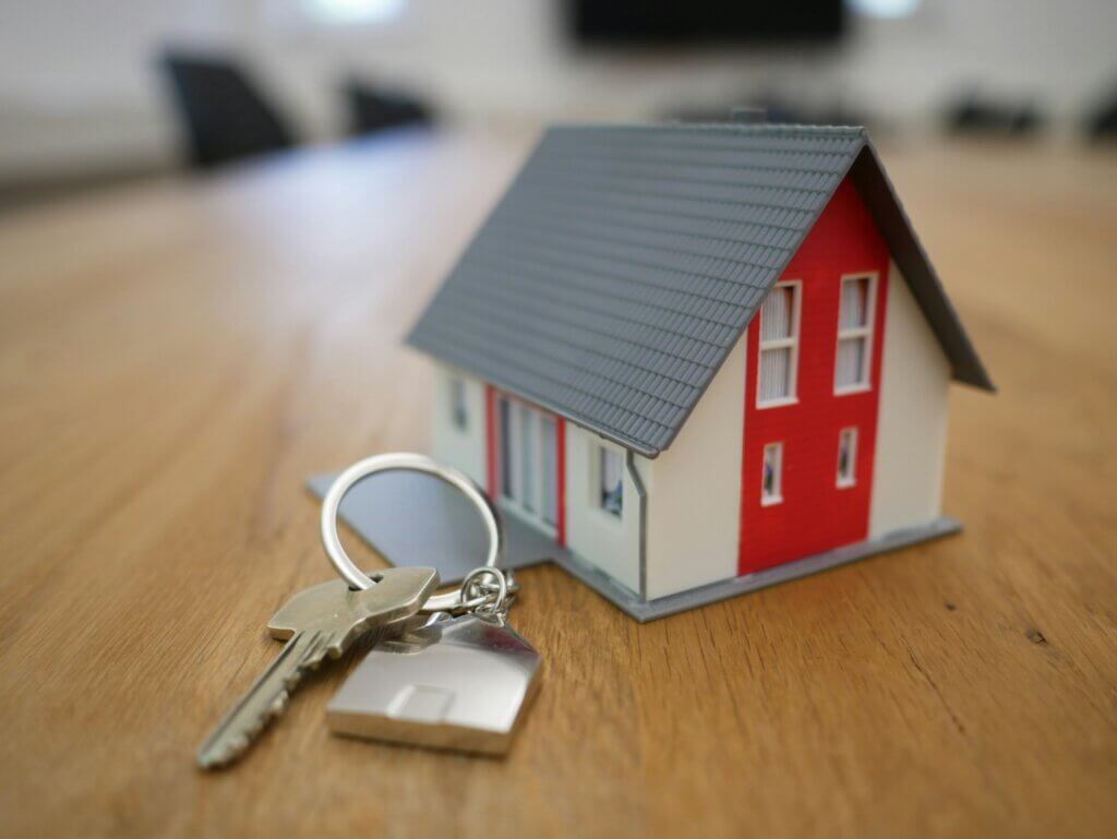 Miniature house and keys on keyring on a wooden conference table