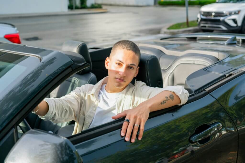 Man sitting in a convertible car in a parking lot