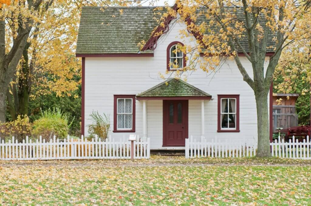 A white house under maple trees.