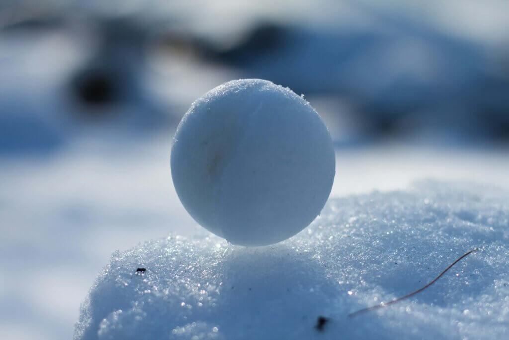 Snowball glittering atop a mound of white snow